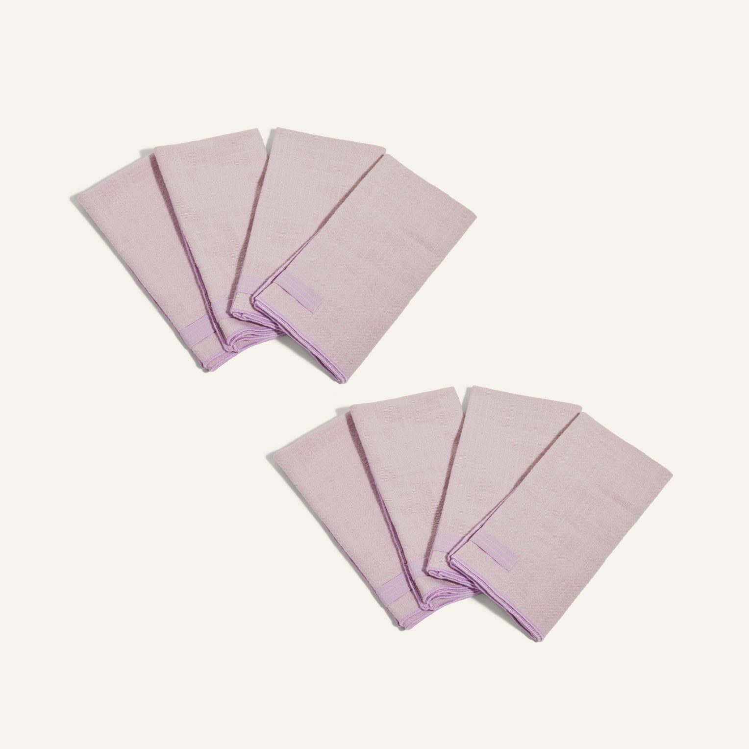Two sets of four folded light purple Loop Napkins are arranged on a plain light background.