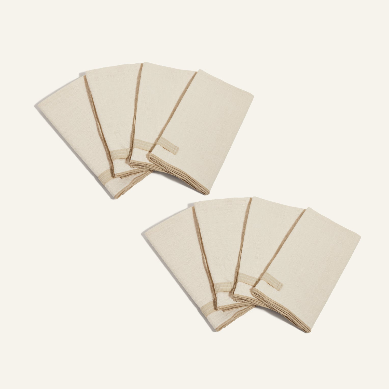Two sets of Loop Napkins in beige, each with a built-in loop ring, are folded neatly and arranged on a light background.
